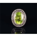 A 14ct yellow gold, silver, diamond, and peridot ring set with an oval-cut peridot (1.5 x 1.0 cm)