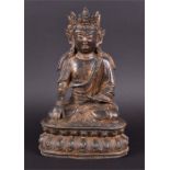 A gilt and painted enamel bronze Tibetan model of Buddha seated in vajraparyankasana on a double