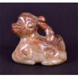 A Chinese carved jade study of a recumbent mythical beast in pale green and russet colours, 5cm wide