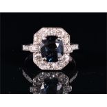 An 18ct white gold, diamond, and sapphire cluster ring set with an oval-cut sapphire of