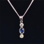 A white metal, diamond and sapphire drop pendant suspended with a round brilliant-cut diamond