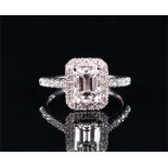 A platinum and diamond ring set with an emerald cut diamond of approximate 0.90 carats,