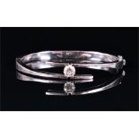 An 18ct white gold and diamond crossover bangle set with a round brilliant-cut diamond of