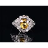 An 18ct white gold, diamond, and yellow sapphire cluster ring in the Art Deco style, set with a