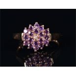 A 9ct yellow gold and amethyst floral cluster ring centred with a diamond accent, size P, 2.2 grams.