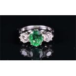 An 18ct white gold, diamond, and emerald ring centred with an oval-cut emerald of approximately 1.80