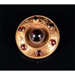 A late 19th / early 20th century yellow metal and garnet brooch of circular form, set with seven