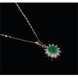 A 9ct yellow gold, diamond, and emerald cluster pendant set with an oval-cut emerald of