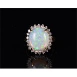 An 18ct yellow gold, diamond, and opal cluster ring set with an oval cabochon opal, surrounded by