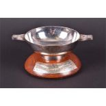 A late 20th century silver quaich on polished hardwood stand with presentation scrip the base with