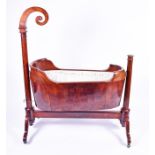 A 19th century French mahogany rocking cradle with scroll head terminal over cylindrical columns