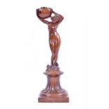 A late 19th century carved walnut candlestick in the form of a classically modelled female nude on a