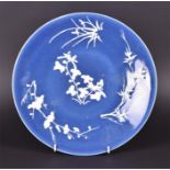 An early 20th century Chinese plate decorated with white glazed cherry blossom and bamboo slightly
