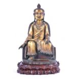 An early 20th century gilt bronze Buddha in serene seated pose, on a bespoke wooden base with