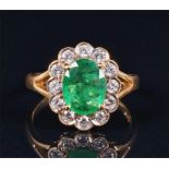 A 14ct yellow gold, diamond, and emerald cluster ring set with an oval-cut emerald of