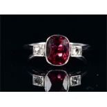 A 9ct white gold, diamond, and tourmaline ring set with an oval-cut pinky-red tourmaline of