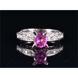 A white gold, diamond, and pink sapphire ring the oval cut pink sapphire of approximately 0.60