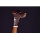 A Victorian child's walking cane the tapering malacca cane terminating in a carved wooden terrier'