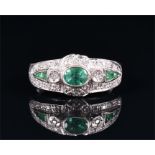 A 14ct white gold, diamond, and emerald ring set with an oval cut emerald to centre, the stylised