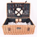 A wicker picnic basket by Regency Hampers Ltd to include flatware, plates, cruets and other items.