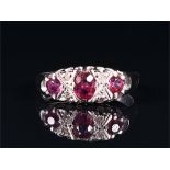 An 18ct white gold, diamond, and ruby ring set with an oval-cut ruby flanked by two round cut