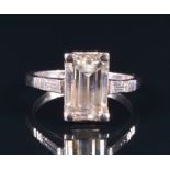 A white metal and diamond ring set with an emerald cut diamond of approximately 2.60 carats,