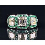 An 18ct white gold, diamond, and emerald ring in the Art Deco style, set with an emerald cut diamond