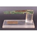 A small ancient bronze axe head presented on a bespoke stand with brass plaque reading 'Canaanite