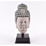 A large Chinese carved stone Buddha's head with limed and painted finish, with a later metalwork
