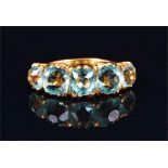 An aquamarine five stone ring the graduated cushion-cut stones claw-set above a heavy yellow metal
