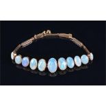 A yellow metal and opal bracelet individually claw-set with eleven graduated oval cabochon opals,