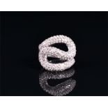 A white metal and diamond ring (shank untested) the swirled mount pave set with round brilliant-