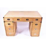 A contemporary oak nine-drawer pedestal desk with campaign style handles, 76 cm high x 119 cm wide x