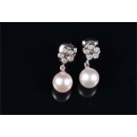 A pair of white metal, diamond, and pearl drop earrings each with a floral cluster of five round