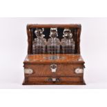 A late Victorian oak three bottle mirror-back tantalus / games box  with silver plated mounts by