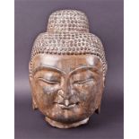 A 20th century carved stone Buddha head in the Khmer style, 24 cm high.