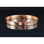 A 9ct yellow gold bangle in the manner of Cartier, with decorative engraved screw-head decoration,