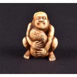 A finely carved 19th century Japanese ivory netsuke in the form of a crouching figure clutching a