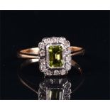 A 9ct yellow gold, diamond, and peridot ring set with an emerald cut peridot surrounded by a