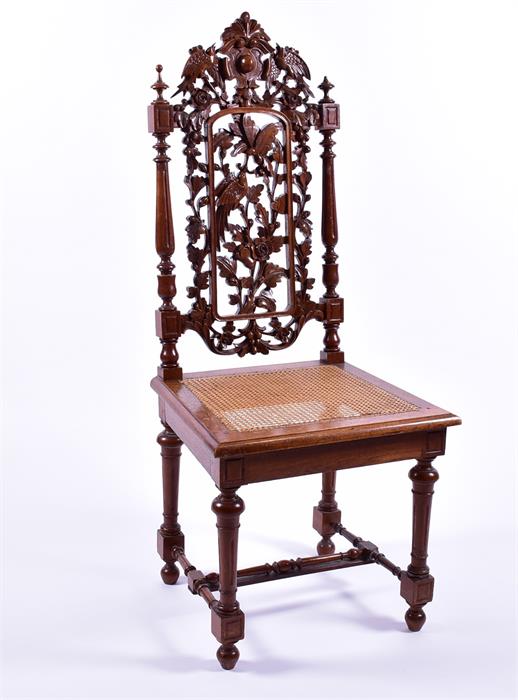 An early 20th century oak side chair with detailed armorial carving over pierced acorn, leaf and