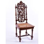 An early 20th century oak side chair with detailed armorial carving over pierced acorn, leaf and