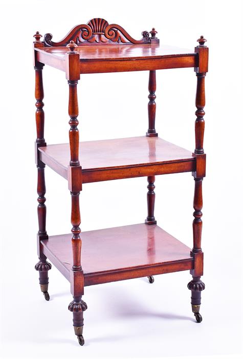 A Victorian mahogany three tier whatnot with carved frieze and turned supports to brass castors.