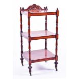 A Victorian mahogany three tier whatnot with carved frieze and turned supports to brass castors.