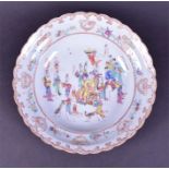 An 18th century Chinese famille rose dish decorated with a robed figure seated in a wheeled chair,