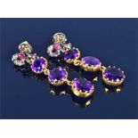 A pair of silver gilt and amethyst drop earrings suspended with three round-cut amethysts, beneath a