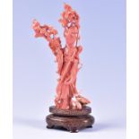 An intricately carved coral 19th century Chinese figure of Guan Yin on a later carved hardwood stand