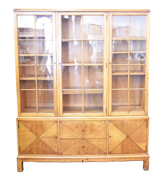 A large early 20th century pale oak triple bookcase with three glazed doors enclosing shelves,