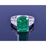 An 18ct white gold, diamond and emerald ring set with an emerald-cut emerald of approximately 6.0