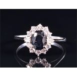 A diamond and sapphire cluster ring set with an oval-cut dark blue sapphire surrounded with round