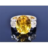 An 18ct yellow gold, diamond, and yellow sapphire ring set with an oval-cut sapphire of